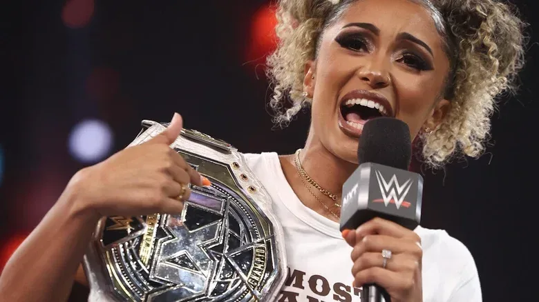 Kelani Jordan speaks into a microphone while holding the NXT Women's Championship on "WWE NXT"