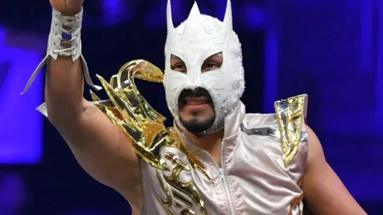 AEW star Komander poses and waves to the crowds on the ropes before a match on an episode of AEW programming.