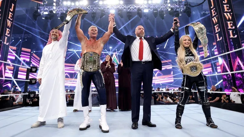 WWE CCO holds the arms of the 2024 Men's and Women's Crown Jewel Champions Cody Rhodes and Liv Morgan, respectively in 2024