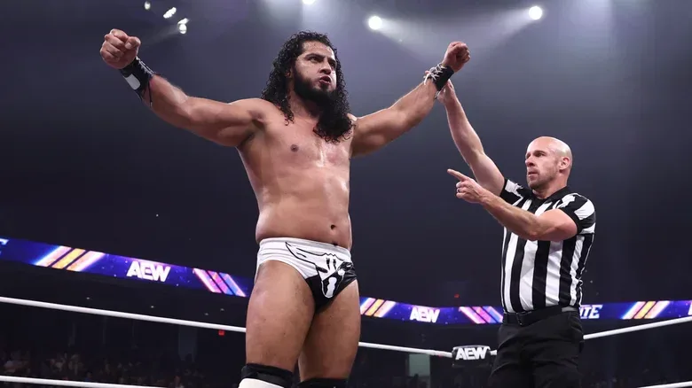A referee holds up the arm of Rush as he stands over a fallen opponent after a victory on an episode of "AEW Dynamite."