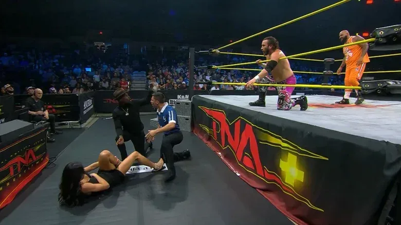 Mila Moore and Expressions outside the ring as John Skyler and AJ Francis wrestle in the ring